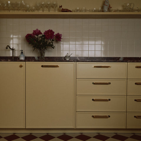 Butter yellow kitchen with unlacquered brass bobbin pulls and backplates